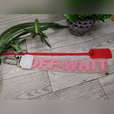 a red and white keychain sitting on top of a wooden floor next to a potted plant