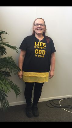 a woman standing in front of a wall wearing a t - shirt that says life is beautiful, god is good