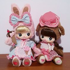 two little dolls sitting next to each other on a table