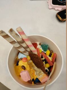 a bowl filled with candy and marshmallows on top of a white table