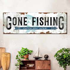 a wooden sign that says gone fishing catch you later on the wall next to some potted plants