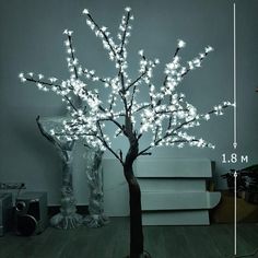 a tree with white lights is shown in front of a gray wall and wooden floor