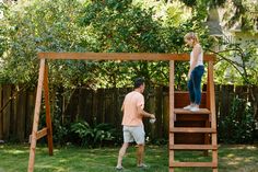 a man standing on top of a wooden ladder next to a woman in a pink shirt