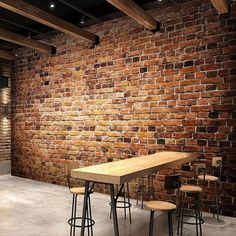 a brick wall with three stools and a table in front of it on the floor