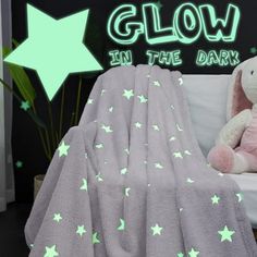 a pink teddy bear sitting on top of a bed under a glow in the dark blanket