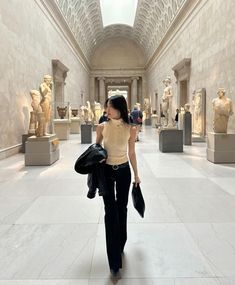 a woman is walking through an art museum with statues on the walls and ceilings behind her