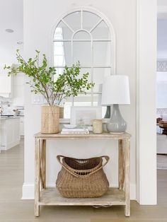 a table with a basket on top of it next to a mirror and vases