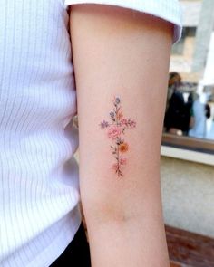 a woman's arm with a cross tattoo on the left side of her arm