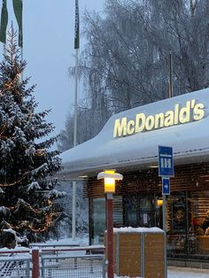 a mcdonald's restaurant in the winter with snow on the ground and christmas trees