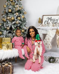 a woman and child in matching pajamas sitting next to a christmas tree