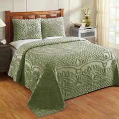 a bed with a green bedspread and pillows