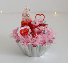 a valentine's day arrangement in a cupcake tin with pink feathers and decorations