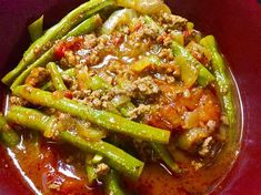 a red bowl filled with green beans and meat