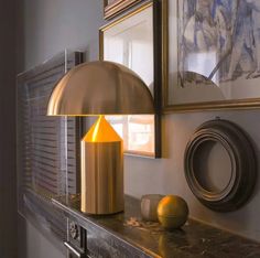 a gold lamp sitting on top of a metal shelf next to a painting and framed pictures