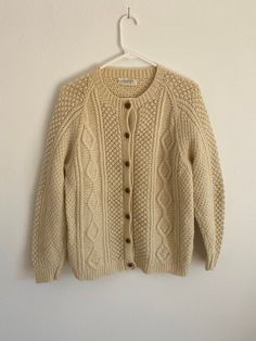 50,s cream colored wool Anna Lewinter Cardigan. Size medium. Both elbows have wear. See photos. One elbow has been mended. The other has not. Not very noticeable at all. Armpit to wrist measures 18 inches. I am a size medium/8 as seen in photos.  All items sold are preowned/vintage. Items will have wear and tear due to age.  Any flaws will be noted in pictures and description. Retro Beige Cardigan For Winter, Retro Beige Winter Cardigan, Classic Beige Sweater For Cold Weather, Vintage Knitted Cardigan For Cold Weather, Vintage Beige Winter Cardigan, Vintage Knitted Beige Outerwear, Vintage Beige Wool Cardigan, Vintage Wool Cable Knit Outerwear, Vintage Wool Cable Knit Cardigan