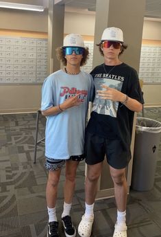 two young men standing next to each other in front of a wall with calendars on it