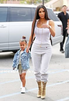 the mother and daughter are walking down the street with their child, who is dressed in white