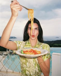 a woman is holding a plate with spaghetti on it and looking surprised at the camera