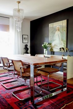 a dining room table and chairs in front of a painting