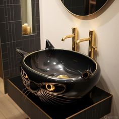 a bathroom sink with a black cat design on the bowl and gold faucet