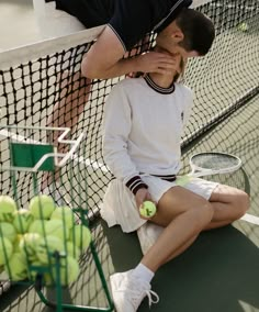 a man sitting on the ground next to a tennis net