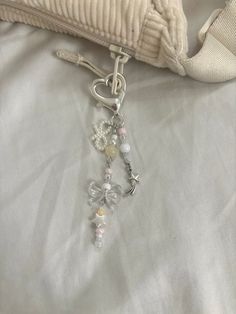 a close up of a key chain on a white bed with a pillow in the background