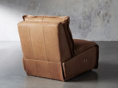 a brown leather chair sitting on top of a cement floor