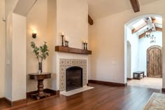 an empty living room with wood floors and a fire place in the middle of it