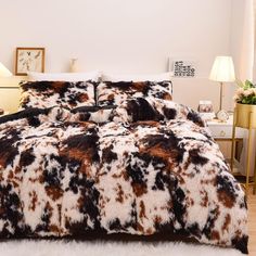 a bed covered in brown and white animal print comforter next to a night stand