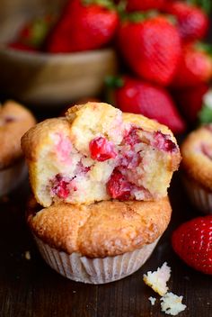 a muffin with a bite taken out of it and strawberries in the background