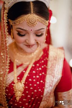 a woman wearing a red and gold bridal outfit looking down at her wedding day