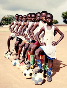 a group of young men standing next to each other on top of soccer balls