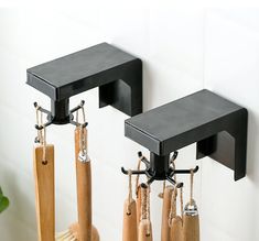 two black wall mounted brackets on the side of a white wall with umbrellas hanging from them