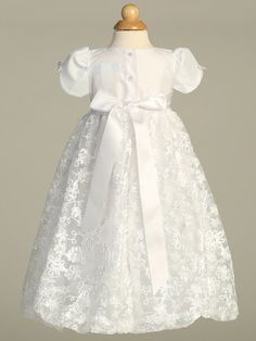 Details This beautiful tulle Christening gown has an embroidered skirt with a floral satin ribbon pattern and a bow accent at the waist. Short puff sleeves with a dainty ribbon bow. Comes with a matching embroidered bonnet. This gown is perfect for a Baptism, Christening, Blessing or any other Special Occasion. Available sizes: X-Small (0-3 months), Small (3-6 months, Medium (6-12 months), Large (12-18 months) 100% Polyester Hand wash cold. Do not use bleach. Hang dry. Made in the USA by Lito Ch Fitted Tulle Baptism Dress With Bow, Fitted Dress With Bow For Confirmation, Tulle Baptism Dress With Bow, Organza Baptism Dress With Bow, Organza Dress With Bow For Baptism, Formal Tulle Gown With Lace Trim, Fitted Baptism Dress With Floral Applique For Dress-up, Fitted Princess Baptism Dress In Organza, Fitted Tulle Baptism Dress With Short Sleeves