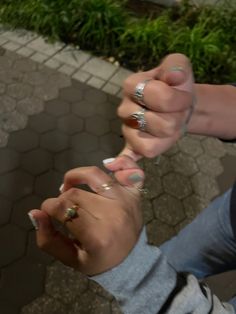 two people are holding hands with rings on their fingers and one is pointing at the other