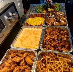 several trays of food sitting on top of a counter next to an oven and microwave