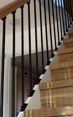 a cat sitting on top of a wooden banister next to a stair case in a house