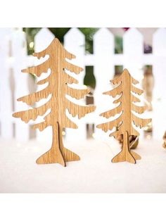 two wooden trees are standing next to each other in front of a white picket fence