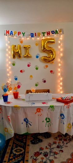 a birthday table with balloons and handprints on it