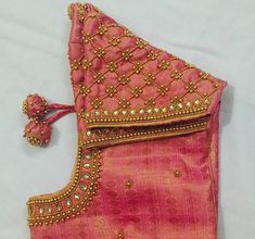 an embroidered pink and gold purse with tassels on the side, sitting on a white surface