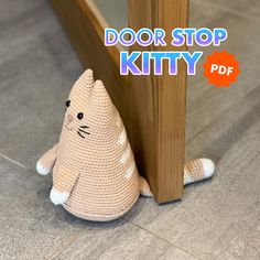 a crocheted cat sitting next to a wooden door with the words door stop kitty on it