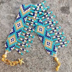 two blue and white beaded bracelets with gold chains hanging from it's sides