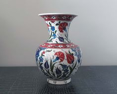 a white vase with red, blue and green flowers on it