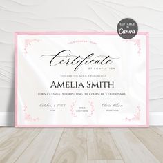 a pink and white certificate is displayed on a wooden floor with a wood floor in the background