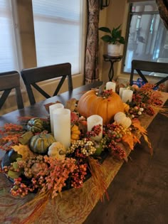 a table with candles, pumpkins and other autumn decorations on it in front of a window