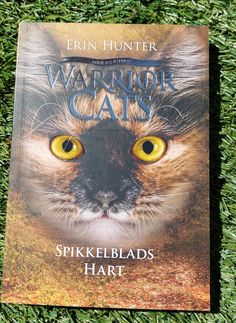 a book about warriors cats is laying on the grass