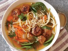 a bowl filled with meatballs, noodles and carrots on top of a table