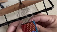 someone is working on an object that looks like a weaving machine with red, white and blue beads