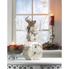 a snowman statue sitting on top of a white table next to a candle holder