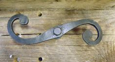 a close up of a metal hook on a wooden surface with holes in the wood